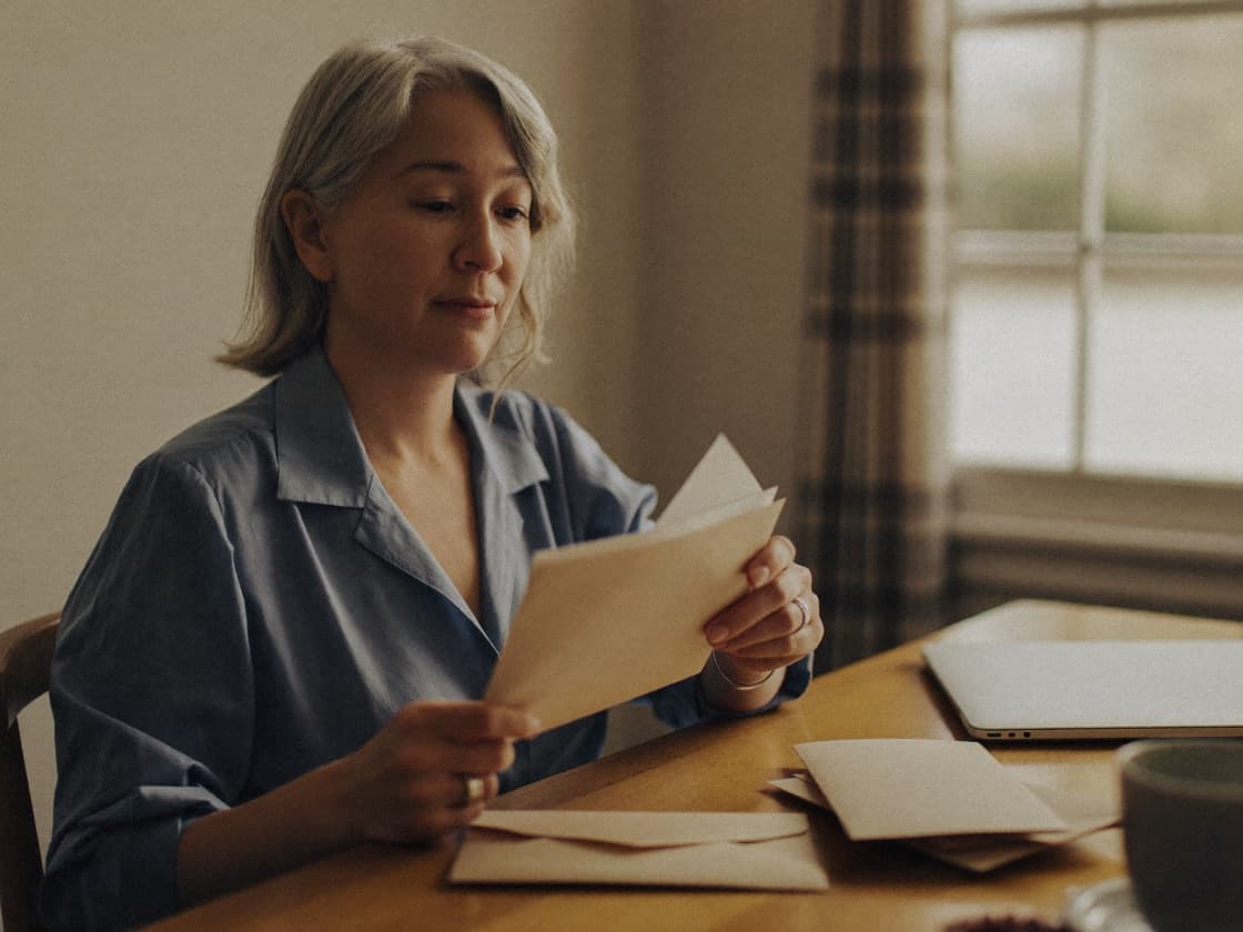 A woman opening letters at her dining table