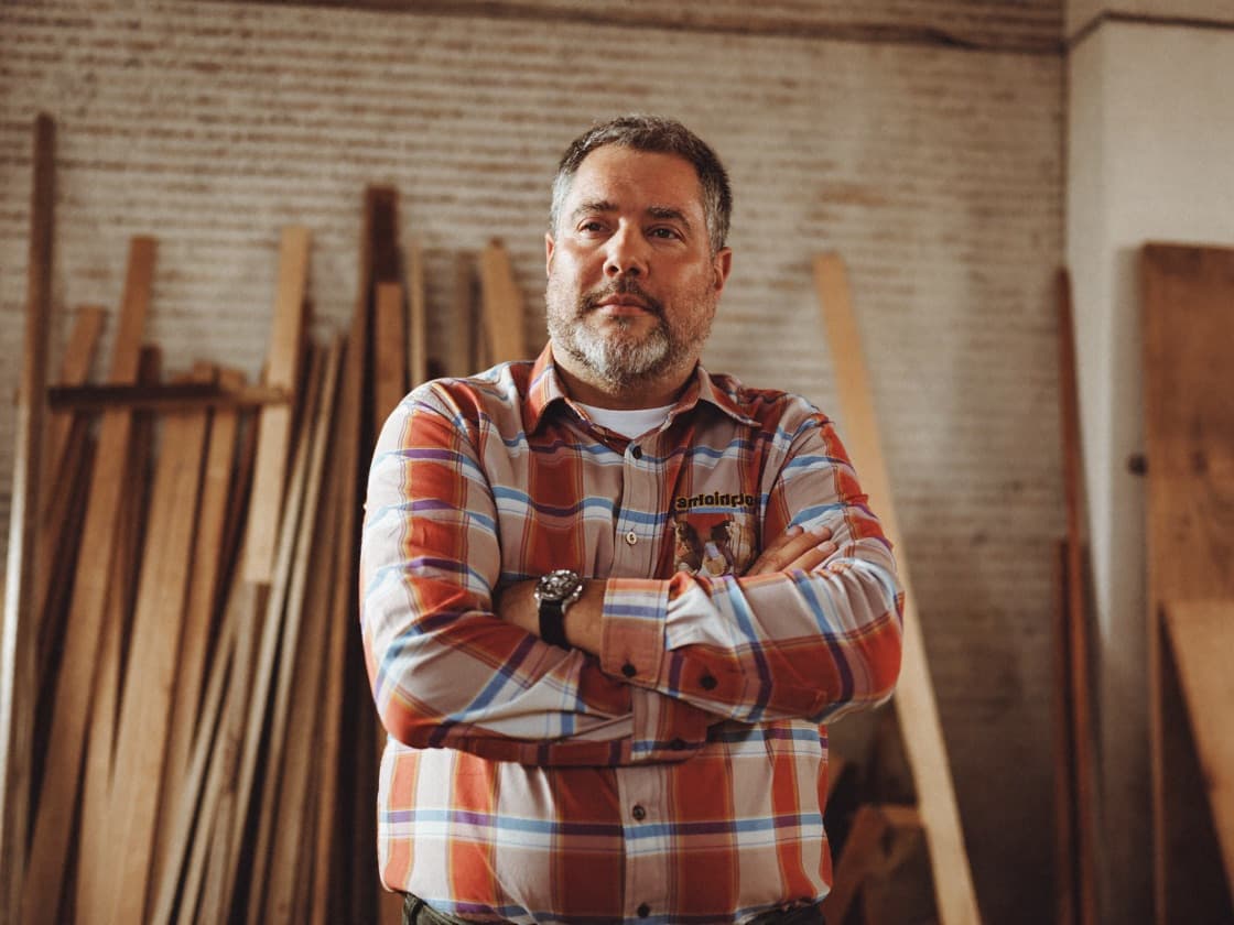 A business owner standing in his workshop with his arms folded