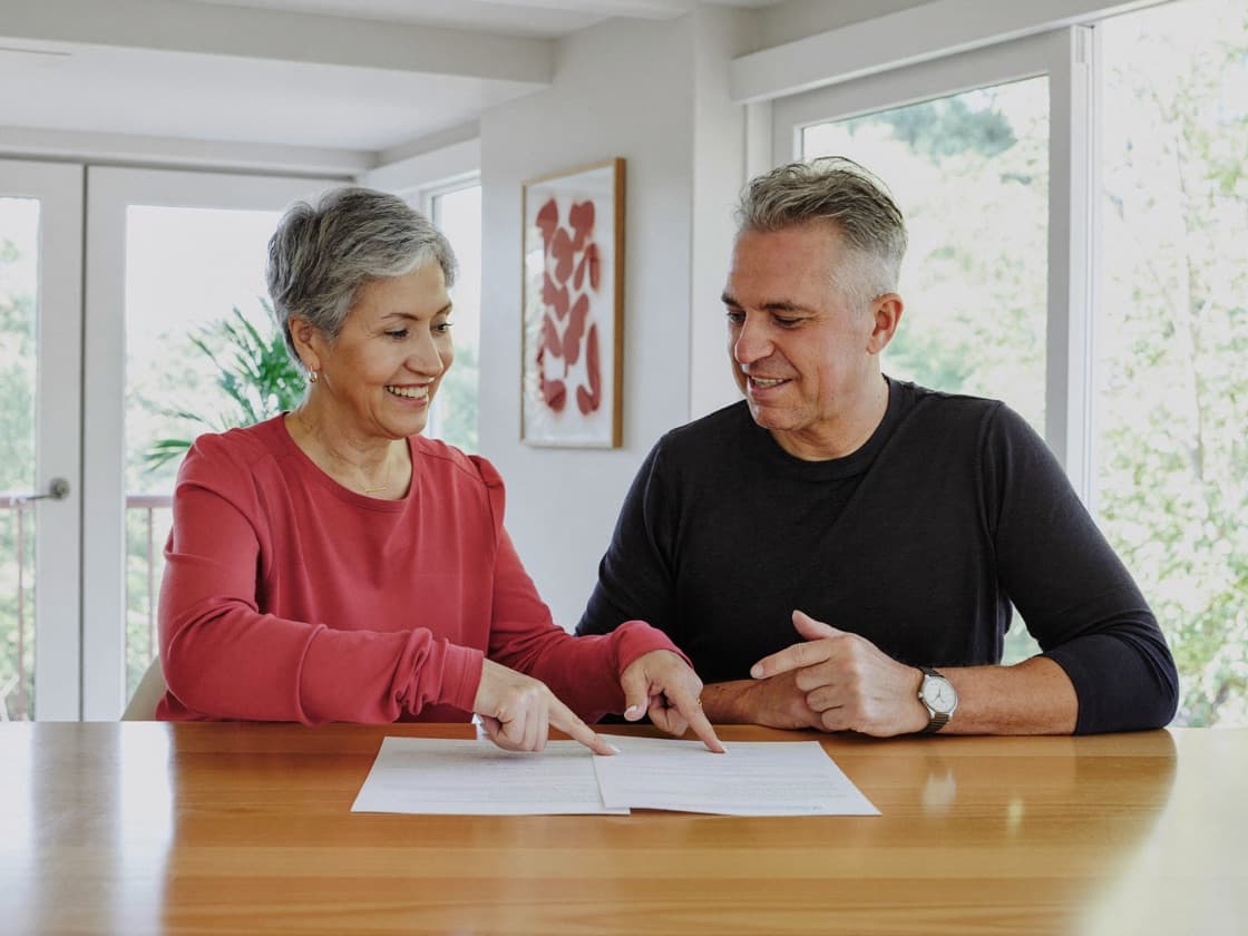 A couple reading through a document together at their kitchen table